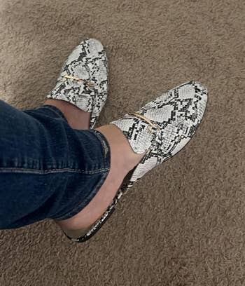 Person wearing snakeskin patterned loafer mules with jeans 