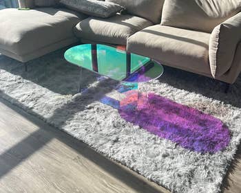 The table near a couch reflecting light on a rug