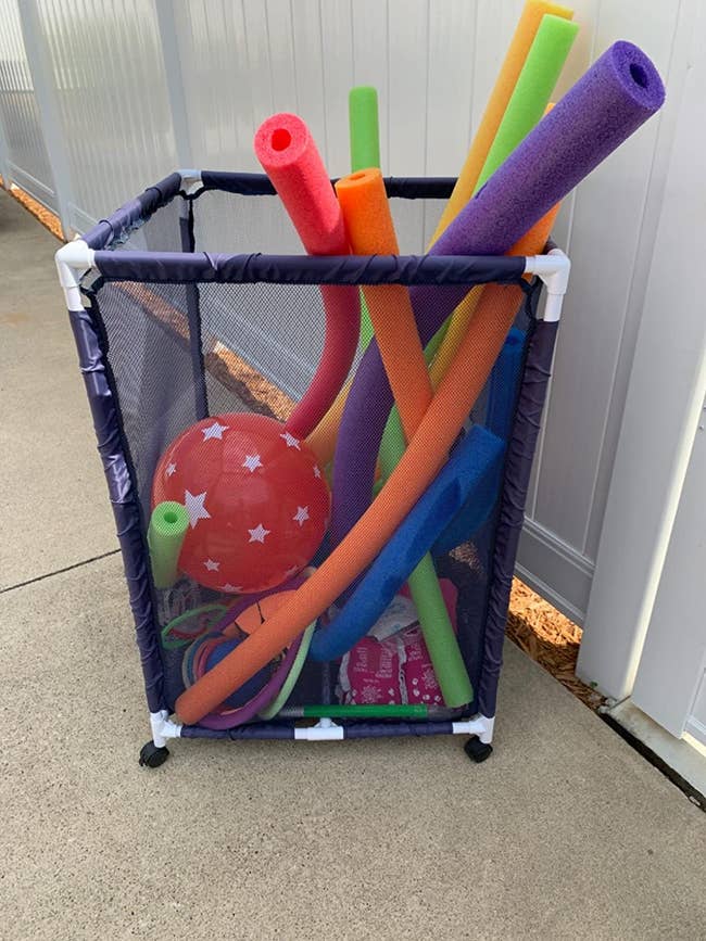 blue mesh organizer holding pool noodles and toys