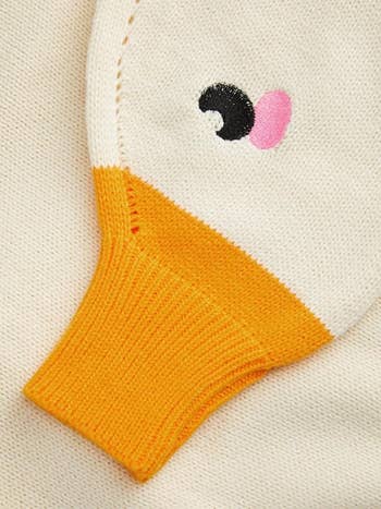 Sweater sleeve with duck-like design featuring a beak, eye, and rosy cheek