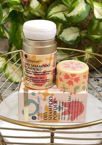 Dry shampoo powder in a small container on top of its box