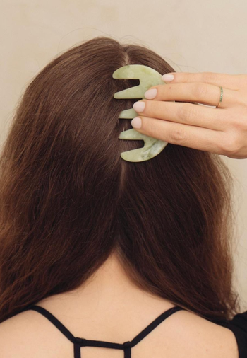 Model using the jade scalp stimulator on the back of their head