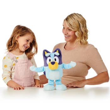 a parent and child playing with the bluey doll