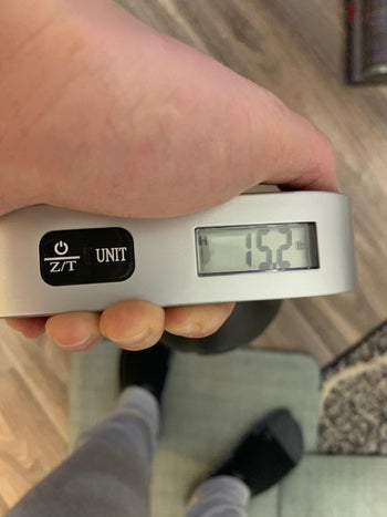 reviewer holding the silver digital scale, which reads 15.2 pounds