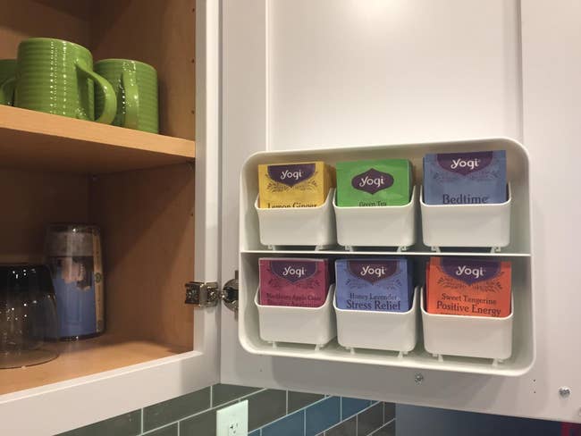 reviewer pic of the tea organizer mounted on the inside of a kitchen cabinet 