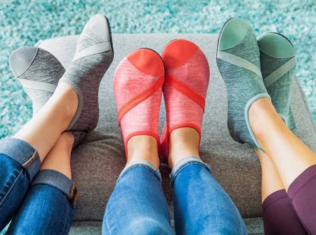 Models wearing sock-like shoes in heathered gray, coral, and mint green colors 