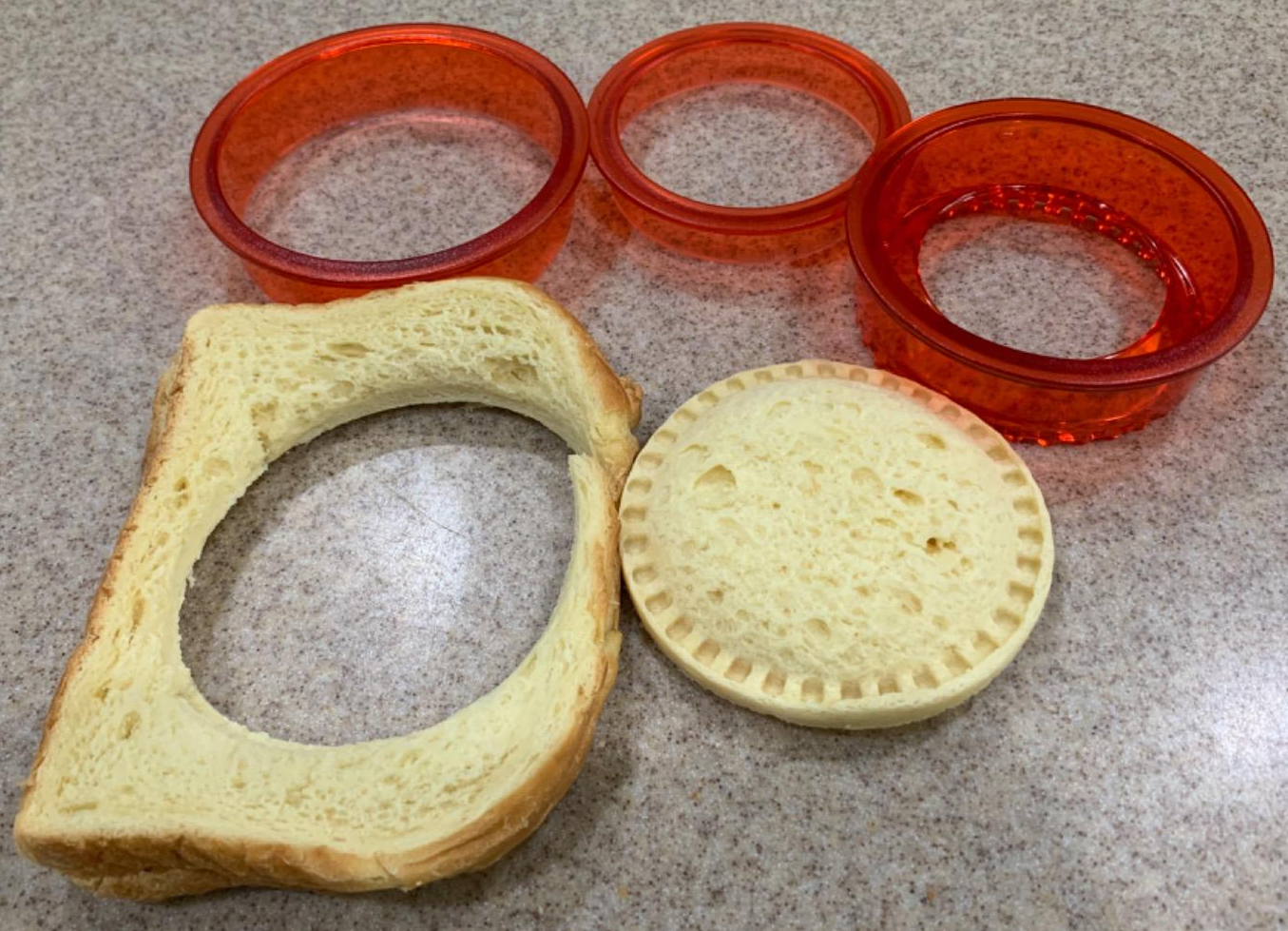 a reviewer photo of the cutter and sealer tool next to a sealed  sandwich and the left behind crust 