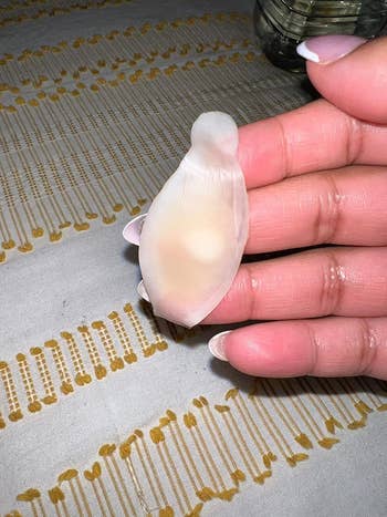 Person holds a translucent silicone bandage filled with pus