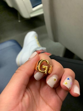 reviewer holding a gold ring with the letter 'g' on it