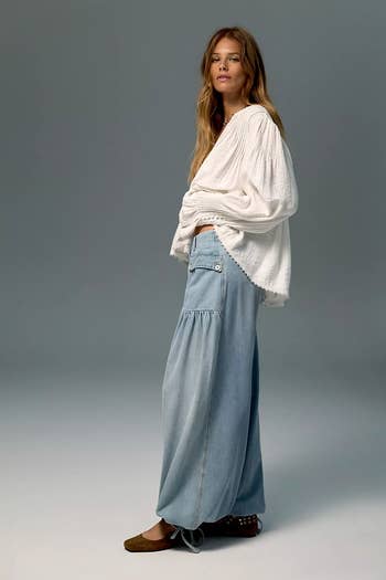 Person successful  flowy outfit with escaped   achromatic  blouse and wide-leg jeans, posing against a plain backdrop. Perfect for casual, comfy  benignant   shopping