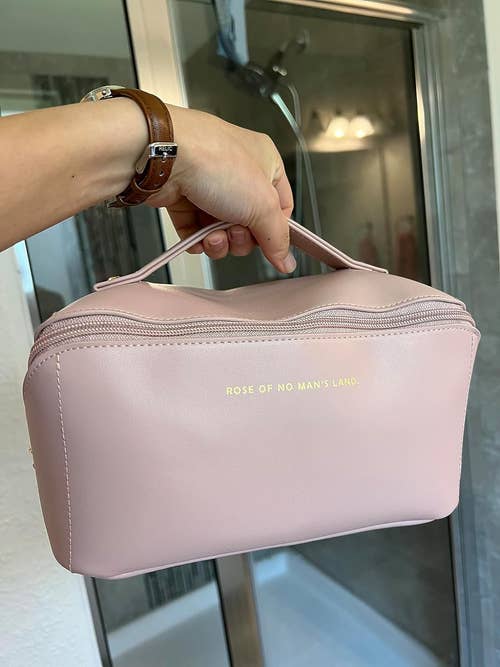 reviewer holding a pale pink cosmetic bag