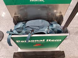 reviewer's light blue backpack placed in the airport personal item bin showing it fits