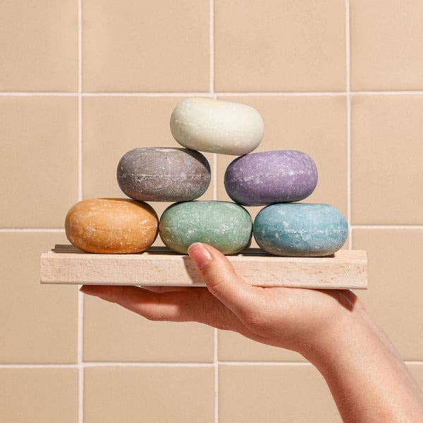 model holding a stack of colorful shampoo bars