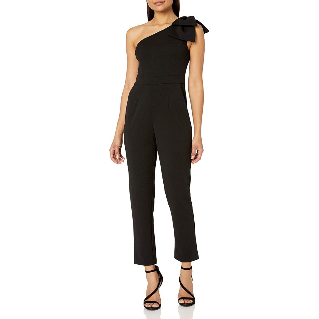 a model in a black one-shouldered jumpsuit with a bow on the shoulder