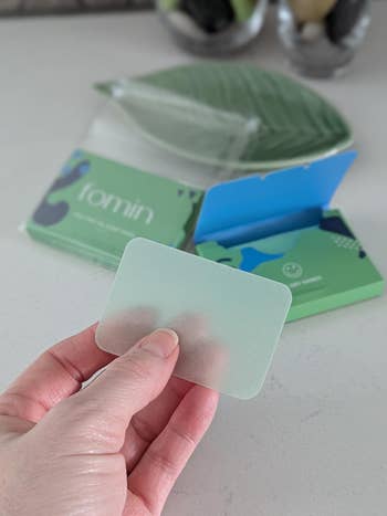 reviewer holding a soap sheet with travel case in the background