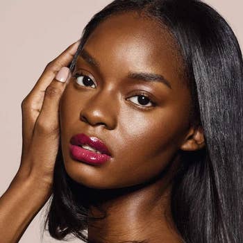 Model poses with glossy reddish  lipstick, touching her face; absorption   connected  constitution  successful  a quality   buying  context
