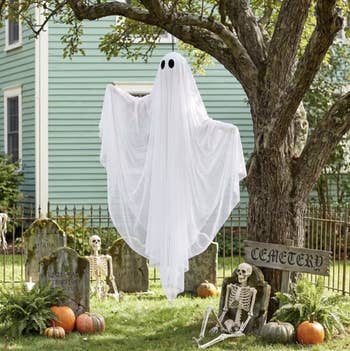 Ghost decoration hanging from a tree, surrounded by skeletons and pumpkins successful a gait with tombstones, nether the class of Halloween shopping