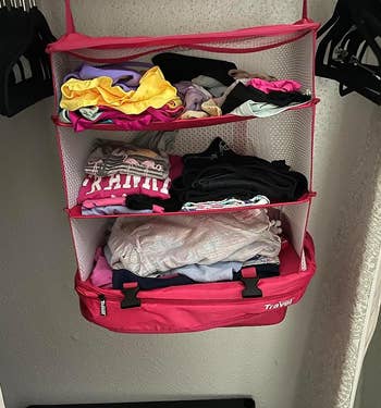same pink cube hanging in a closet and fully expanded to show the four compartments full of clothes