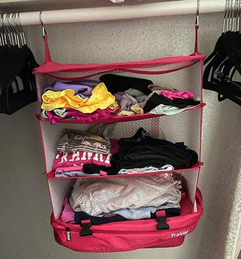 same pink cube hanging in a closet and fully expanded to show the four compartments full of clothes