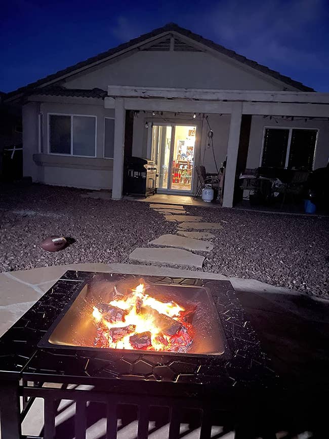 reviewer's fire pit with fire in the foreground with a house in the background