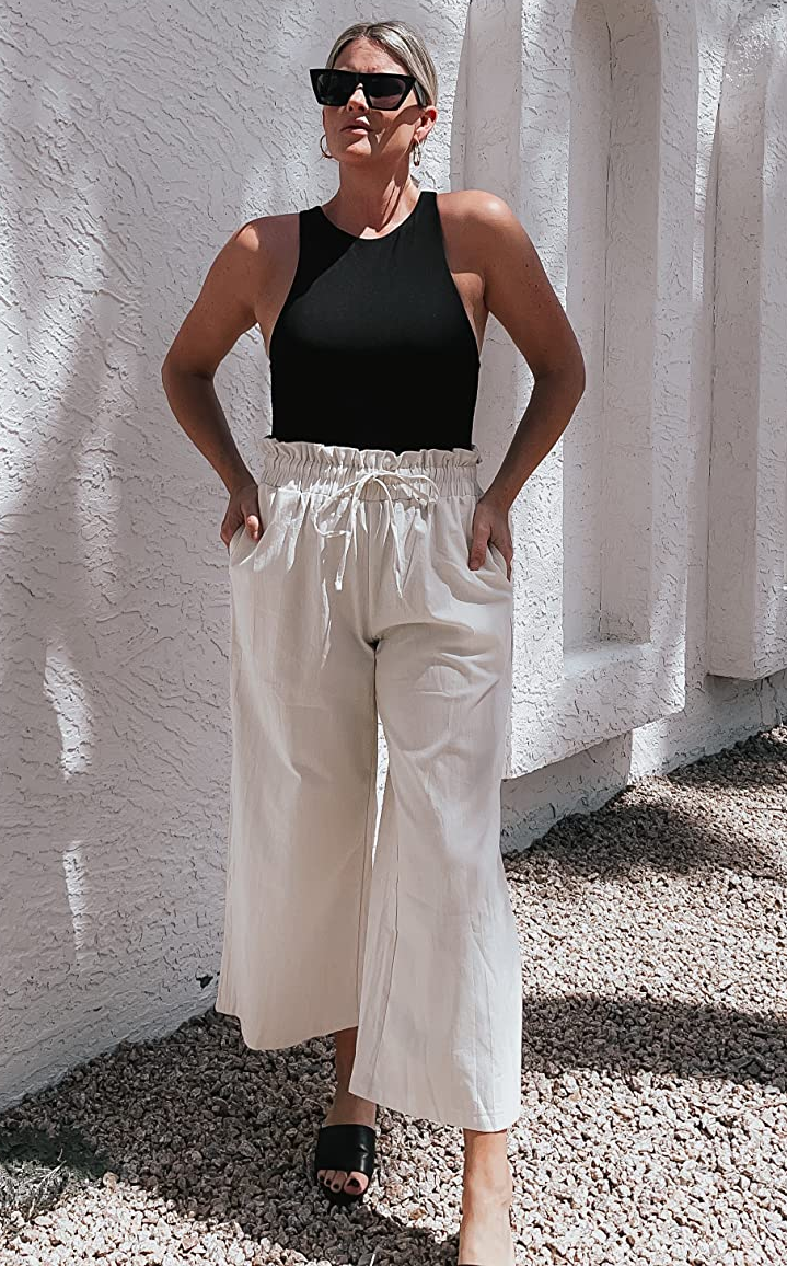 reviewer wearing the white pants with a black tank and sandals