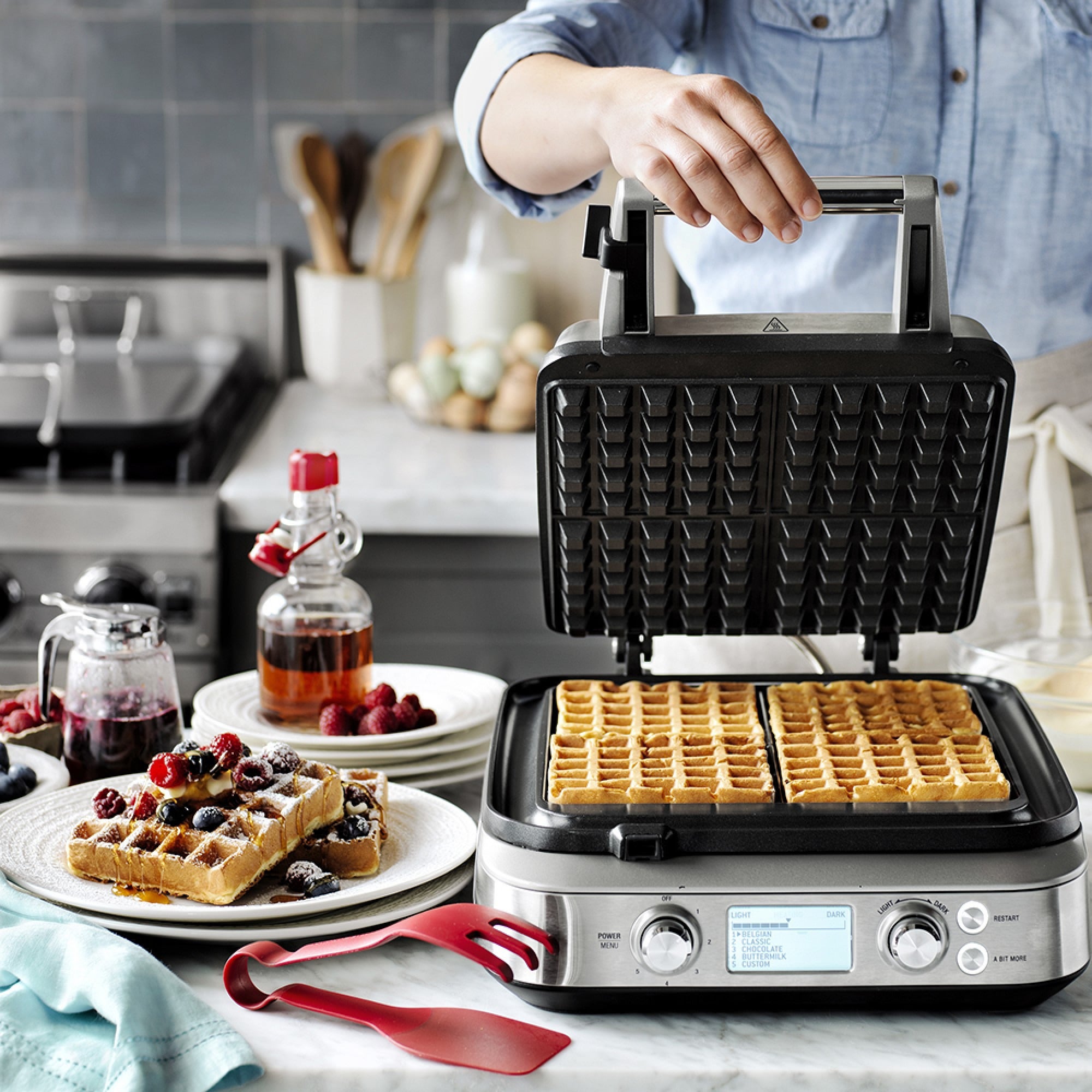 Waffles cooking in opened waffle maker placed on kitchen counter
