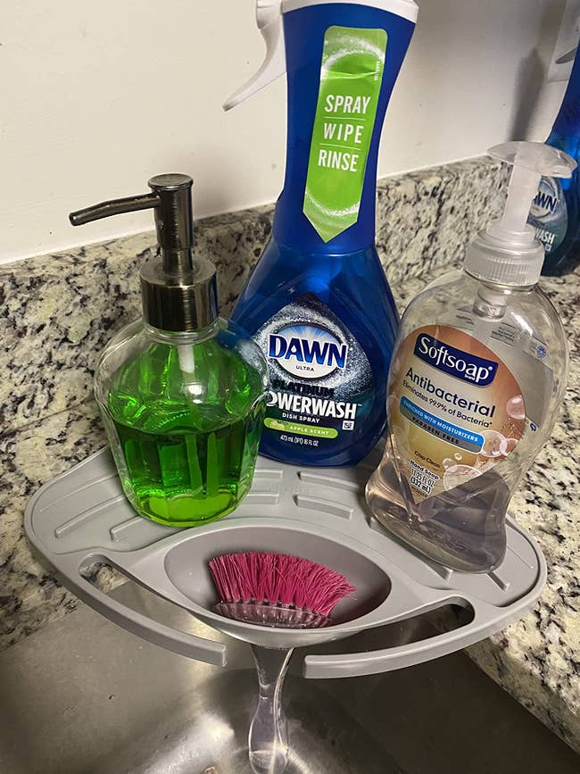 Kitchen sink organizer with Dawn Powerwash, Softsoap antibacterial soap, a green soap dispenser, and a dish brush. Perfect for cleaning essentials