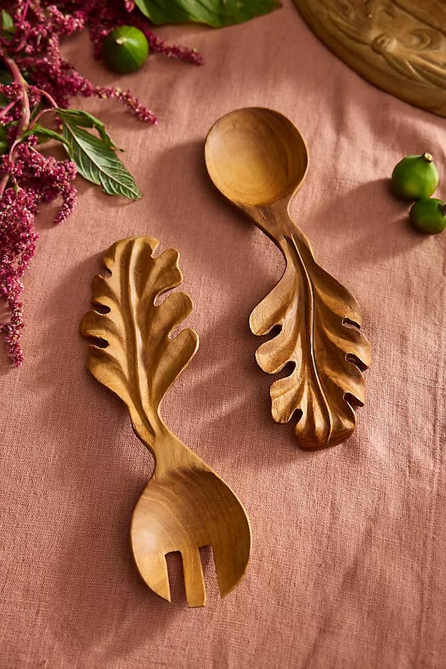 Wooden serving fork and spoon acceptable   with carved leafage  handles, displayed connected  cloth  with decorative greens, perfect  for nature-themed dining