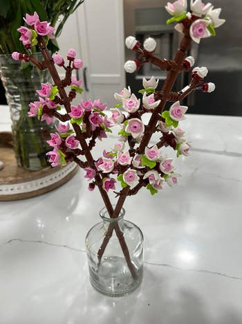 Lego pink and white flowers arranged in a glass vase on a kitchen counter