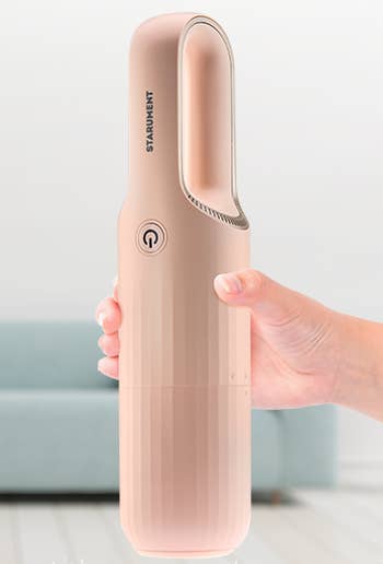 model's hand holding the pink vacuum with its cover on