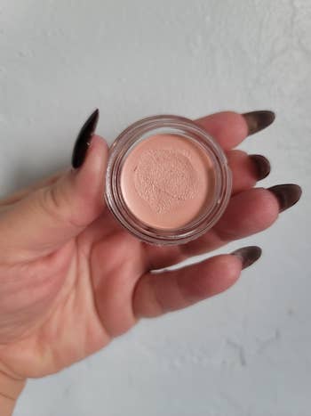 Person holding a tiny  instrumentality  of pick  makeup