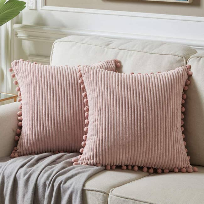 two pink pom pom pillows on a couch