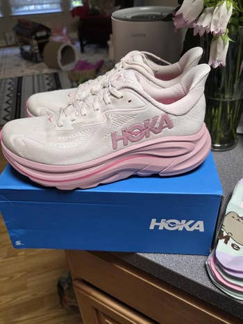 Hoka running shoes with thick soles on a blue box, displayed on a counter