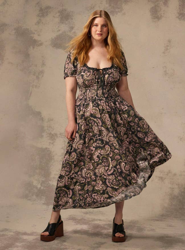 Person wears a bohemian-style formal  with paisley patterns and level    sandals, posing against a neutral backdrop. Suitable for a manner  feature