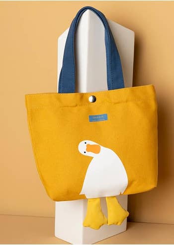 Tote container  with a slouching duck design, bluish  handles, displayed against a neutral background