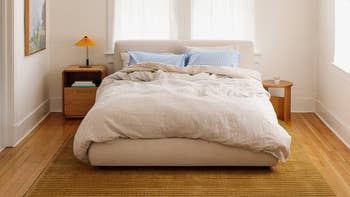Cozy chamber  setup featuring a neatly made furniture  with neutral bedding, 2  pillows, bedside tables, a lamp, and brushed  earthy  light