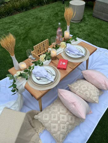 photo of romantic picnic table set up on blanket with pillows