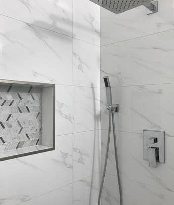 Modern shower with rainfall head, handheld nozzle, and niche with mosaic tiles