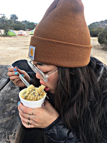 reviewer wearing brown beanie eating noodles