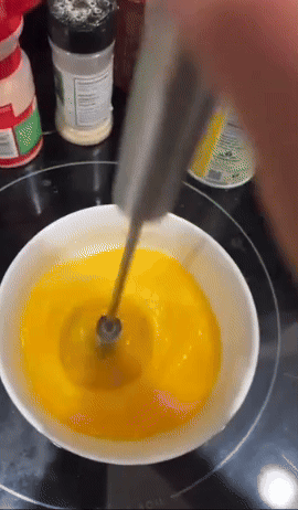 Reviewer pressing down on the rotating whisk to beat eggs 