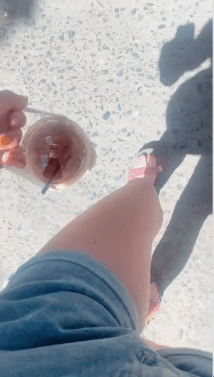 editor using the handled holder to walk down the street with iced coffee 