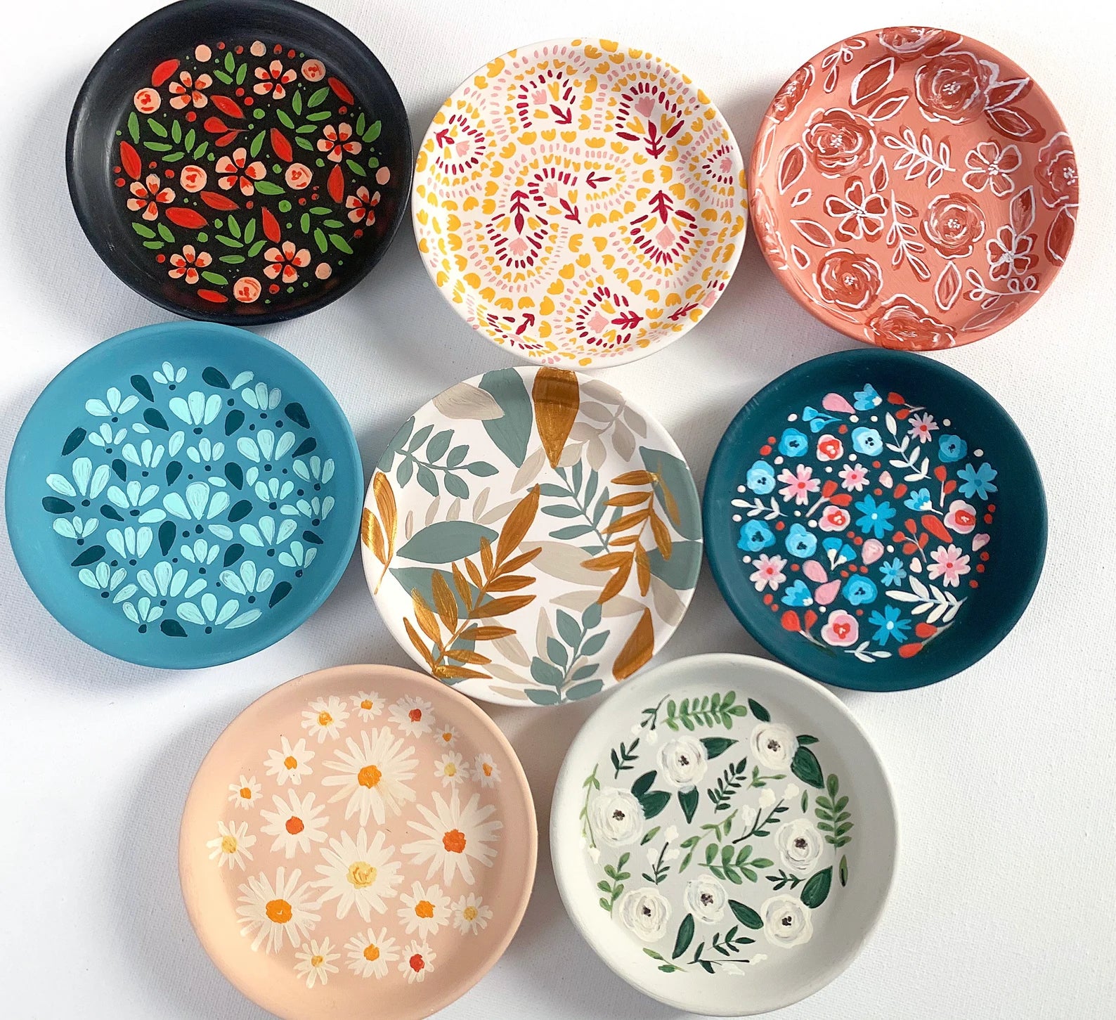 eight round trinket dishes in various hand-painted designs