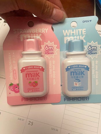 hand holding two of the bottles of correctional tape