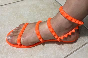 the orange studded sandal on a foot