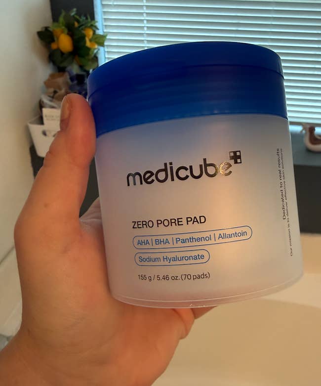 Hand holding Medicube Zero Pore Pad instrumentality successful a bath setting