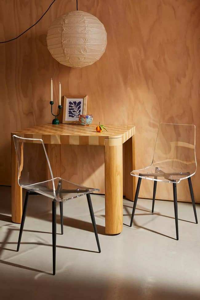 Wooden table with contemporary distinct acrylic chairs and decorative devices, for a dwelling interior inspiration article