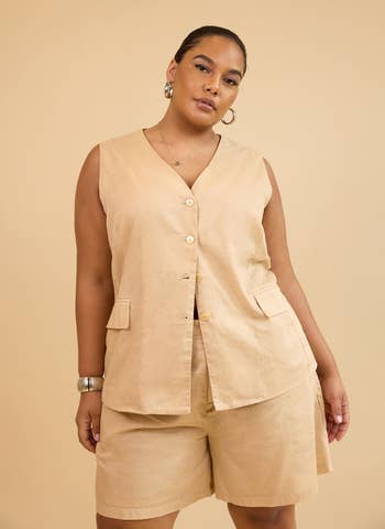 Person wearing a sleeveless button-up vest and shorts, styled with hoop earrings and a bracelet. Casual, minimalist fashion