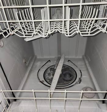 Empty white dishwasher interior with open racks and visible sprayer arms. Ideal for discussing cleaning appliances