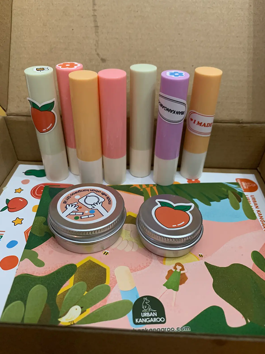 Reviewer image of box with seven lip balms and two lip balm tins on top of stickers and a card
