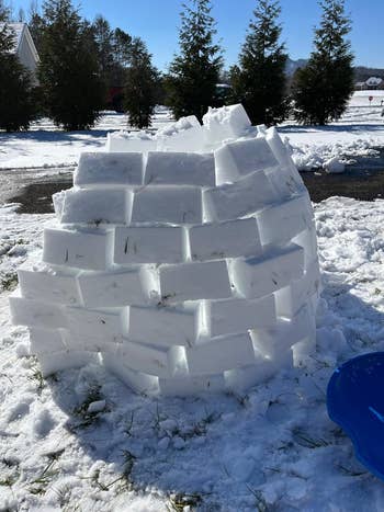 An igloo built with snowfall  blocks stands successful  a snowy yard